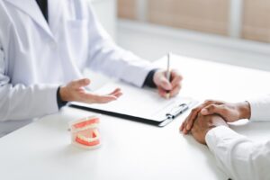 Dentist showing a dental implant model to a patient during a consultation